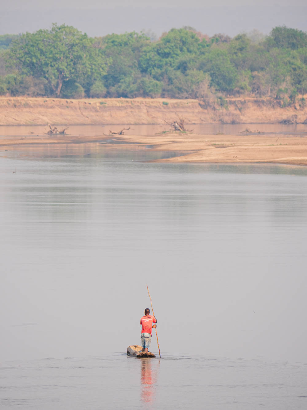 Local fisherman punts his dugout canoe on the Luangwa river